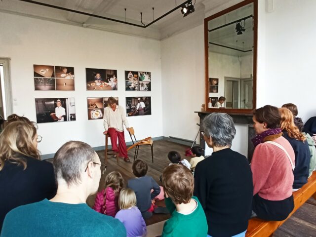 Un groupe de parents et d'enfants écoutent l'histoire racontée par un conteur.