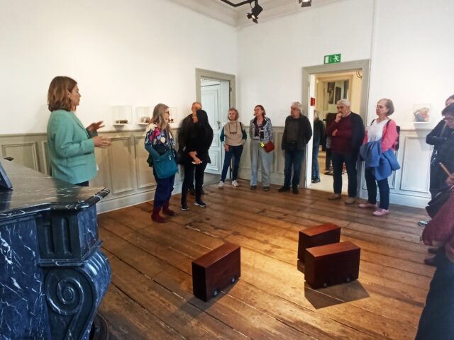 Groupe de personnes écoutant un guide expliquer les œuvres qui les entourent dans la pièce.